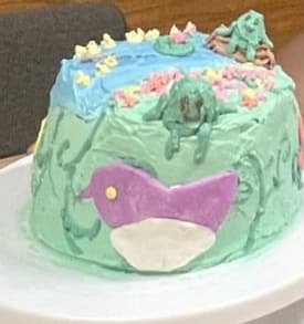 Frog on a log with a pond of ducks